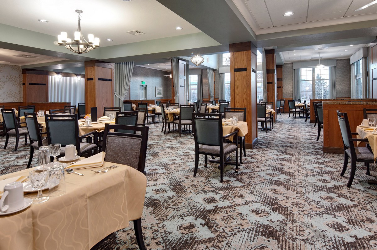 An elegant restaurant dining area with neatly arranged tables and chairs, featuring a carpeted floor.