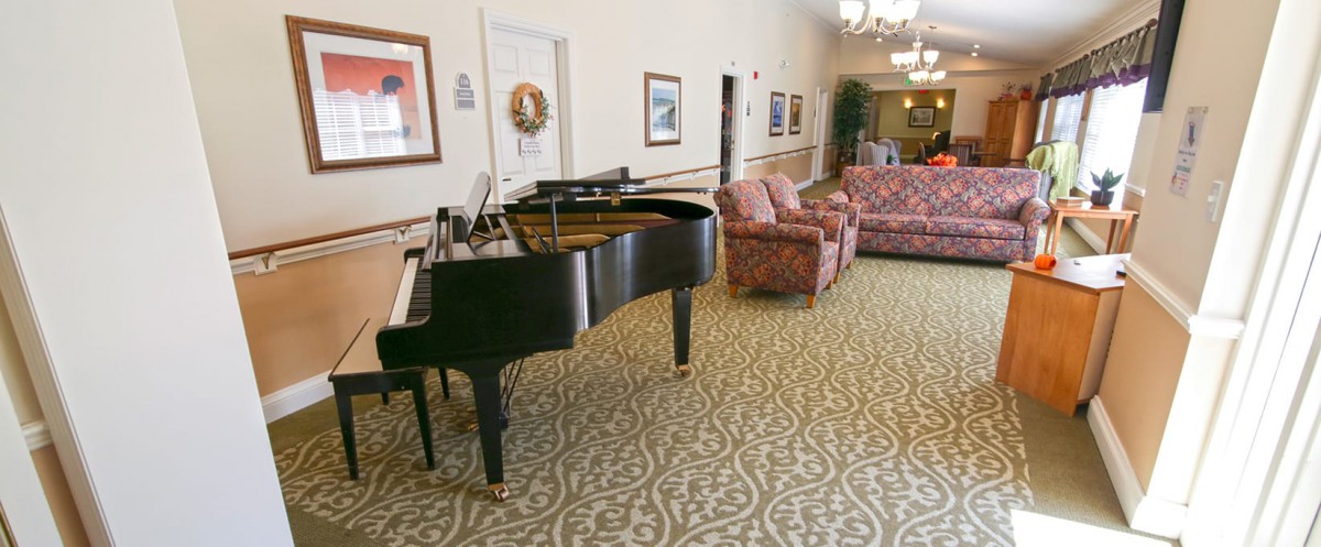 A lobby with a grand piano, patterned carpet, and comfortable seating arrangements.