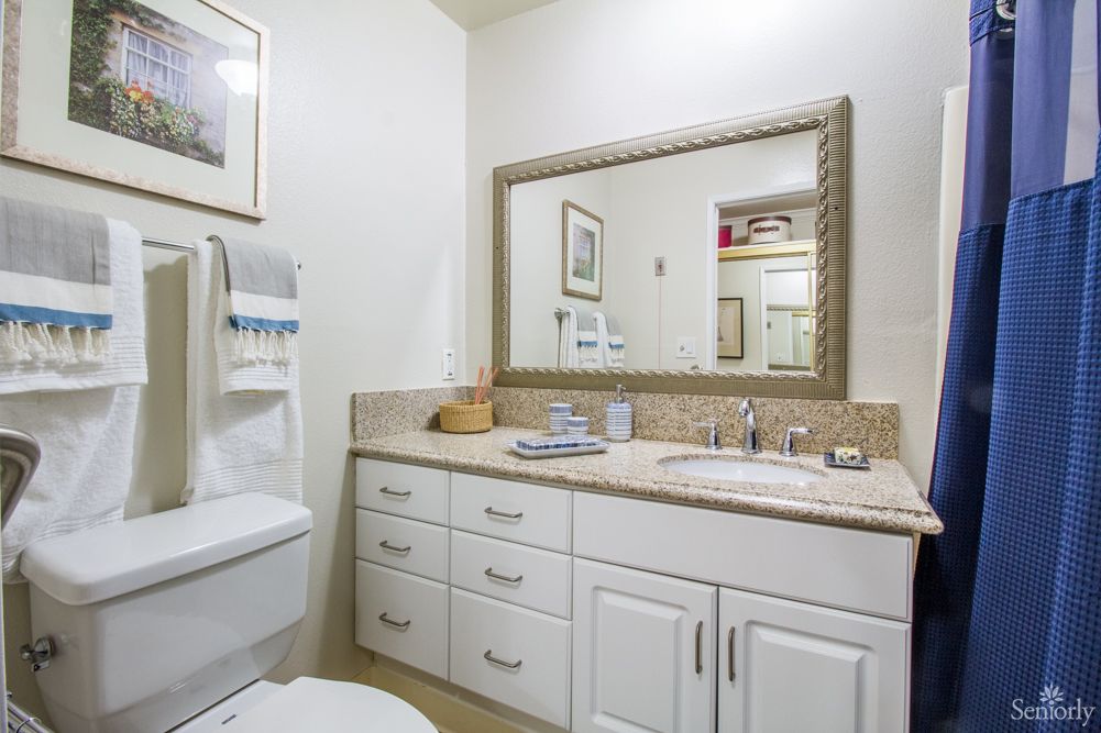 A bright and modern bathroom with white cabinets, a large mirror, and neatly arranged towels.