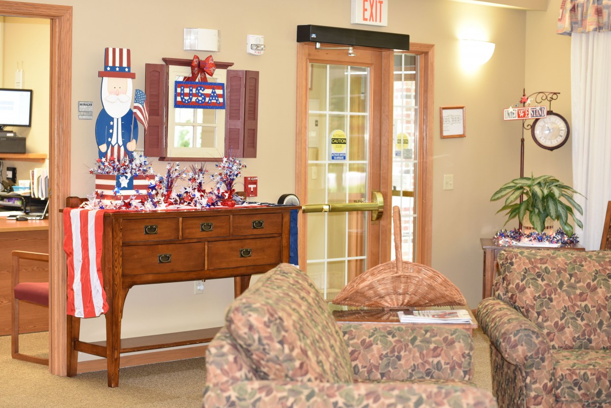 A cozy lobby area decorated with patriotic themes, featuring a sofa, a decorated table, and an American flag motif.
