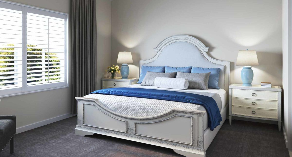A well-appointed bedroom featuring a stylish bed with a blue and white color scheme, accompanied by coordinated pillows and a bedside lamp.