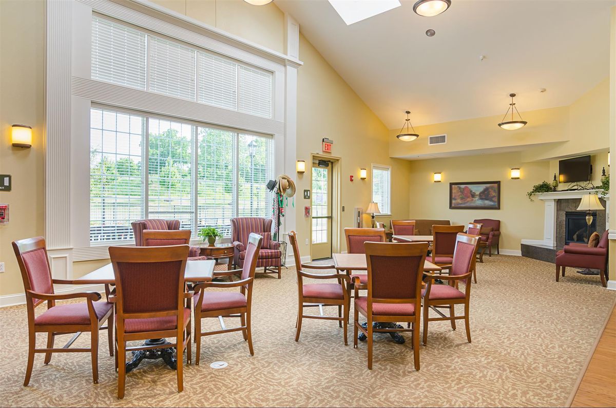 A well-lit dining area featuring multiple tables and chairs, with large windows allowing natural light to fill the room.