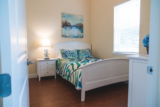 A cozy and well-decorated bedroom featuring a comfortable bed, nightstand with lamp, and colorful artwork.