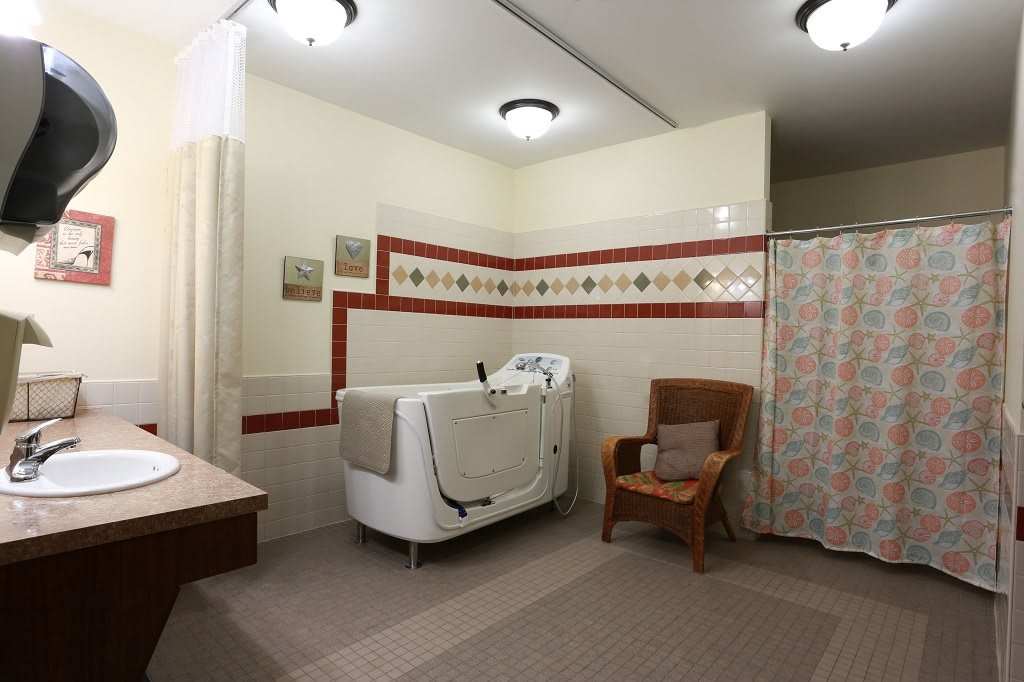 A vintage-style bathroom with a walk-in bathtub and wicker chair.