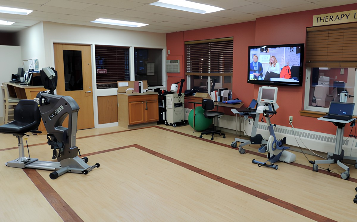 A hospital room with exercise equipment and a TV.