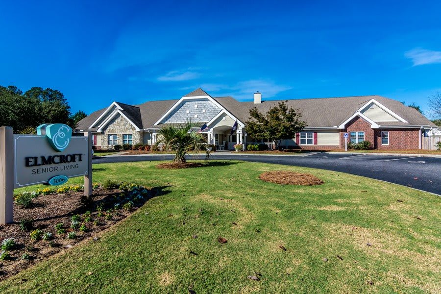 A well-maintained building with a driveway and lush green lawn on a clear, sunny day.
