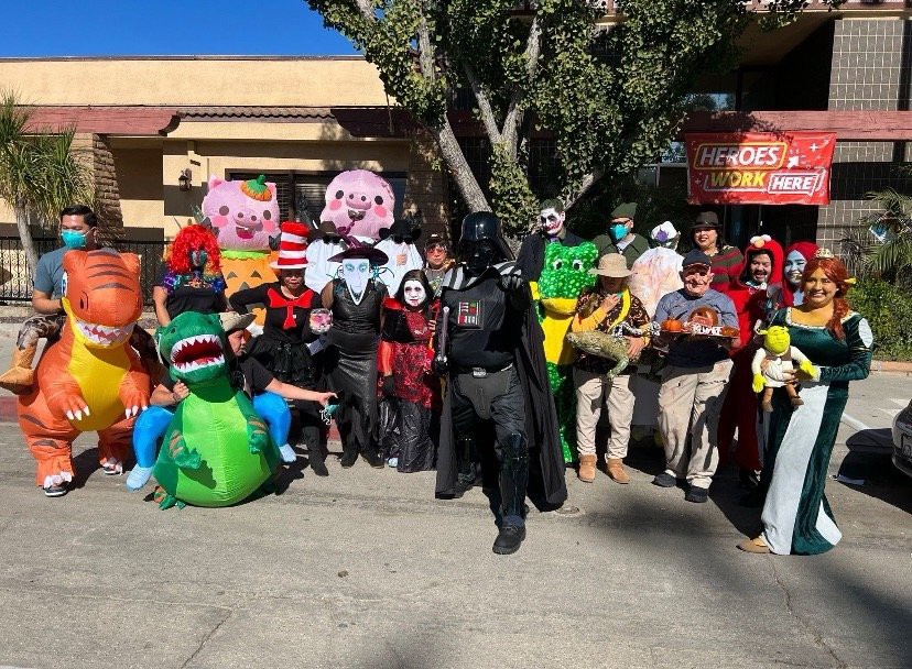 A group of people dressed in various costumes poses outdoors for a fun, festive photo.