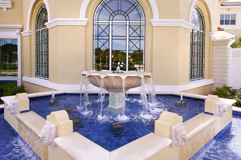 Elegant outdoor fountain with cascading water in front of a large windowed building.