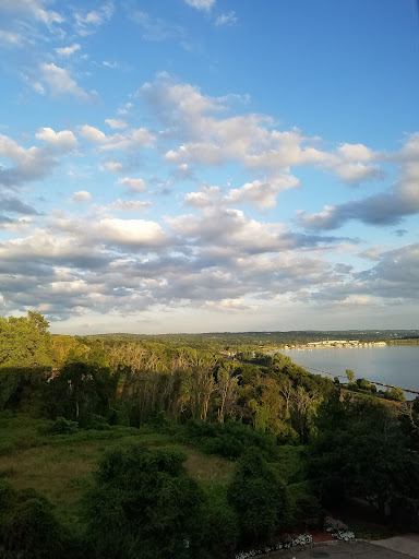 A serene view of the river under a cloudy sky, framed by lush greenery.