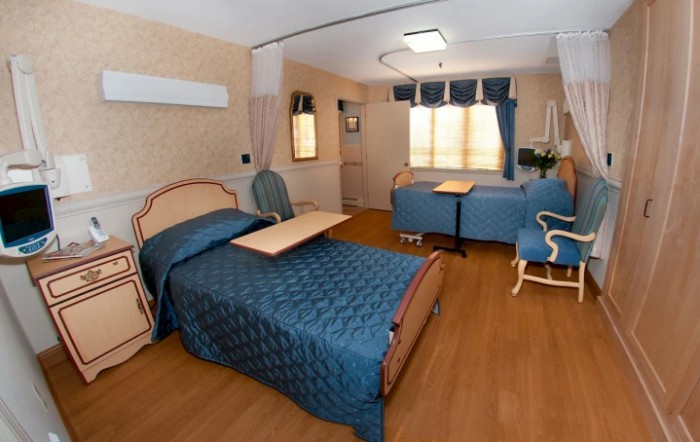 A well-furnished hospital room with two beds and comfortable seating.