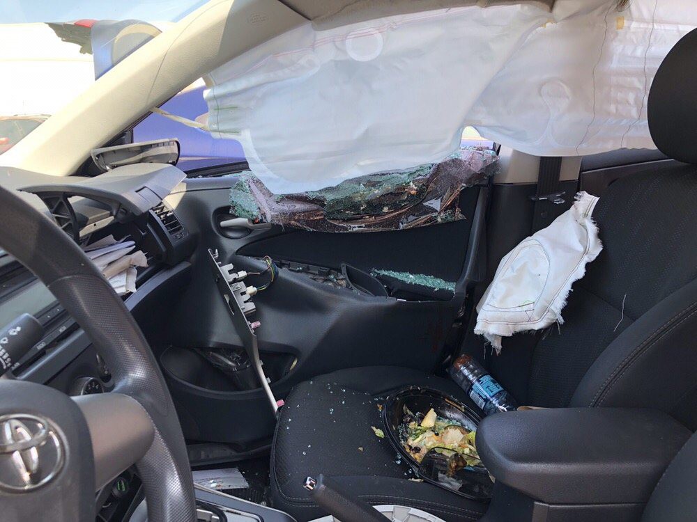 Interior of a car showing deployed airbags and damage from a collision.