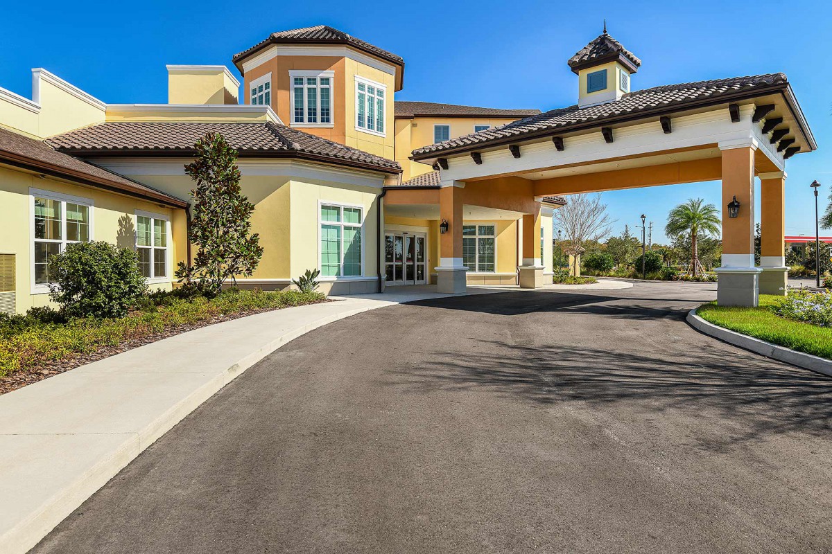 A residential building with a covered entrance and landscaped surroundings on a sunny day.