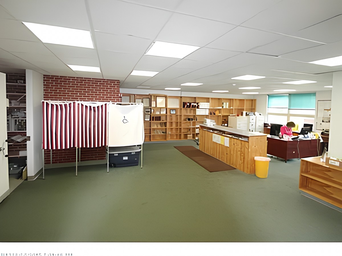 An interior view of a polling station with voting booths and office space.