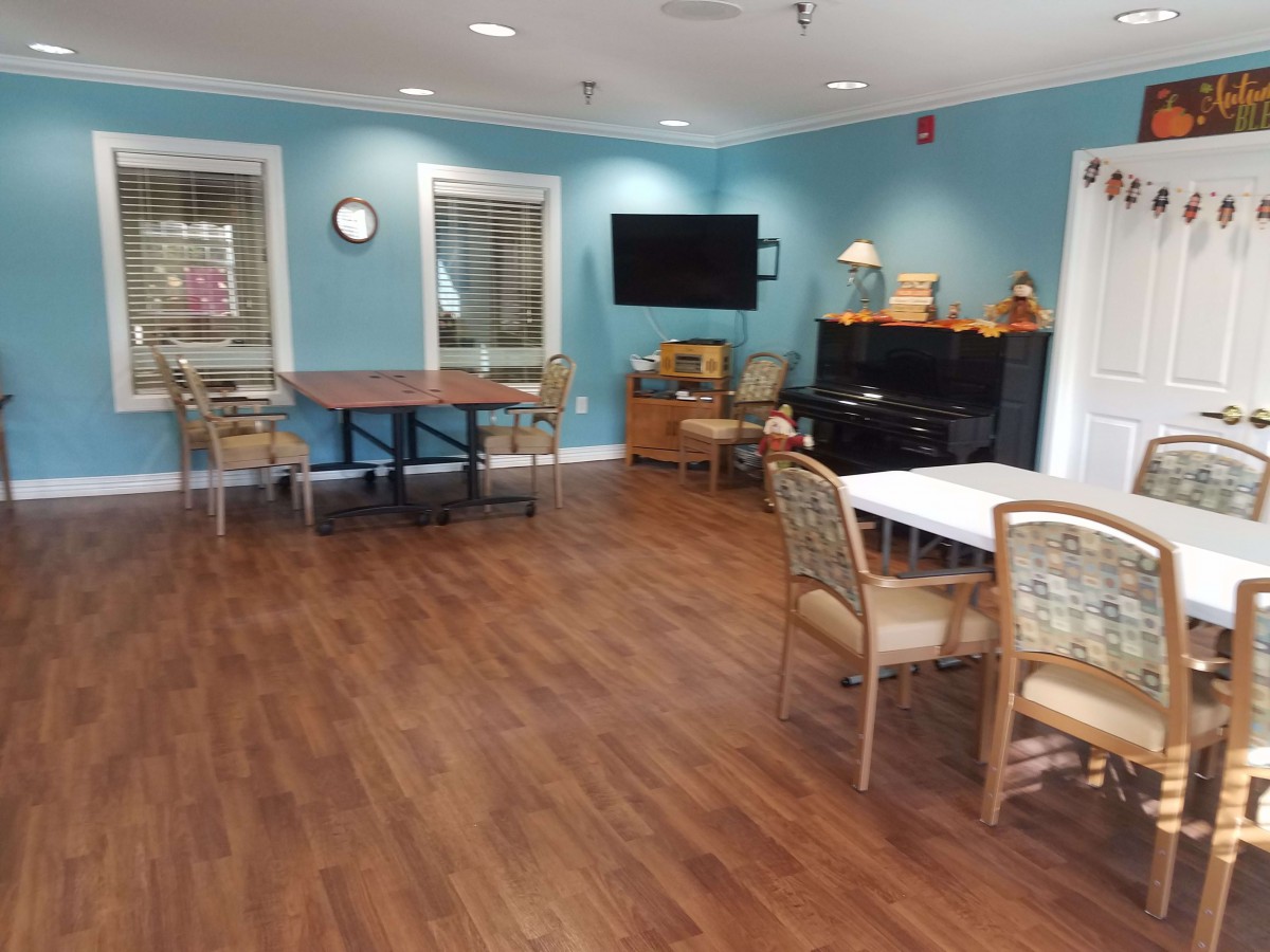 A spacious, well-lit room with tables, chairs, and a television.