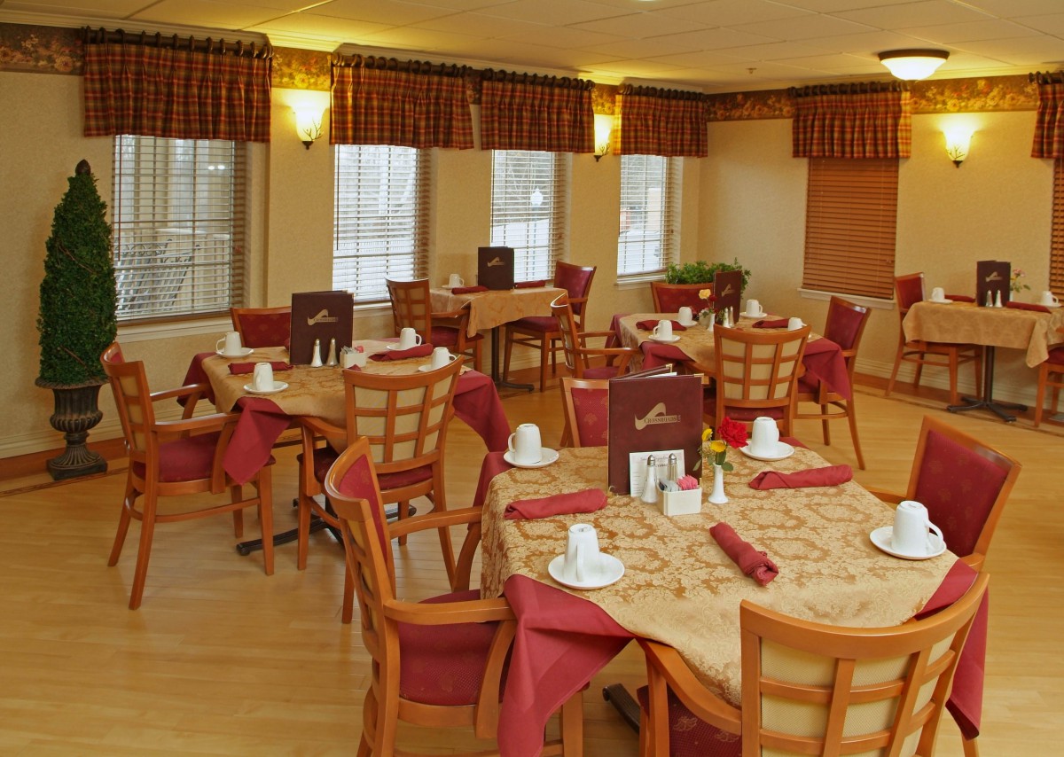 A cozy dining room with well-arranged tables and chairs, featuring elegant table settings and warm lighting.