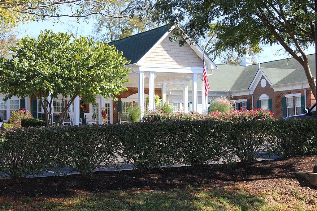 A cozy house with a welcoming front porch surrounded by greenery and trees.