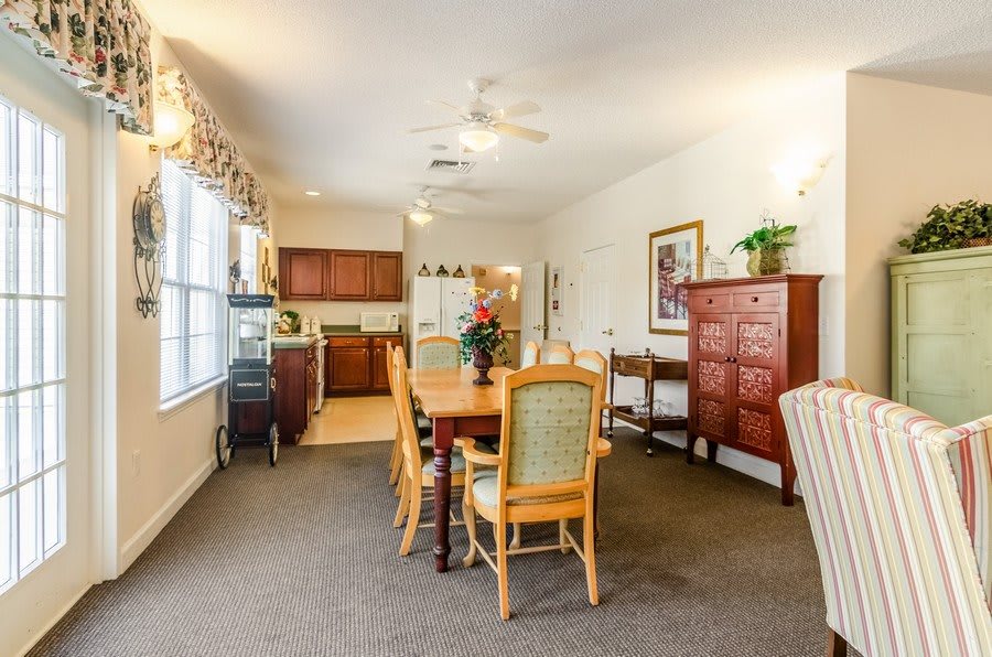 A spacious dining area with a table and chairs, adjacent to a kitchen and complemented by wooden cabinetry and decor.