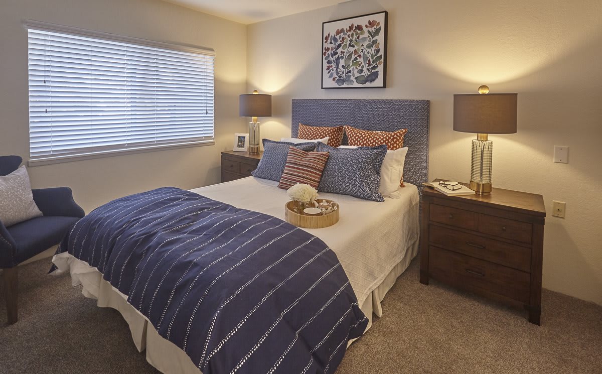 A modern and cozy bedroom with a neatly made bed, decorative pillows, and warm lighting.