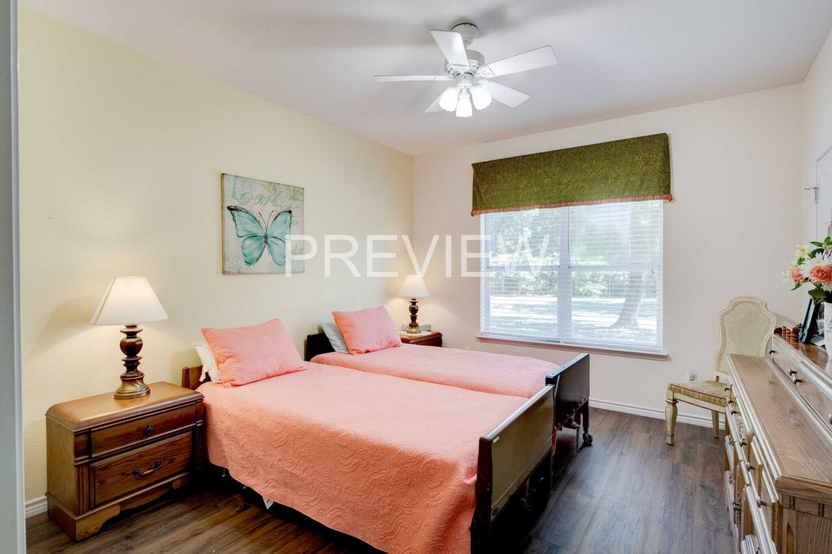 A cozy bedroom with twin beds, decorated in warm tones and lit by natural light from a large window.