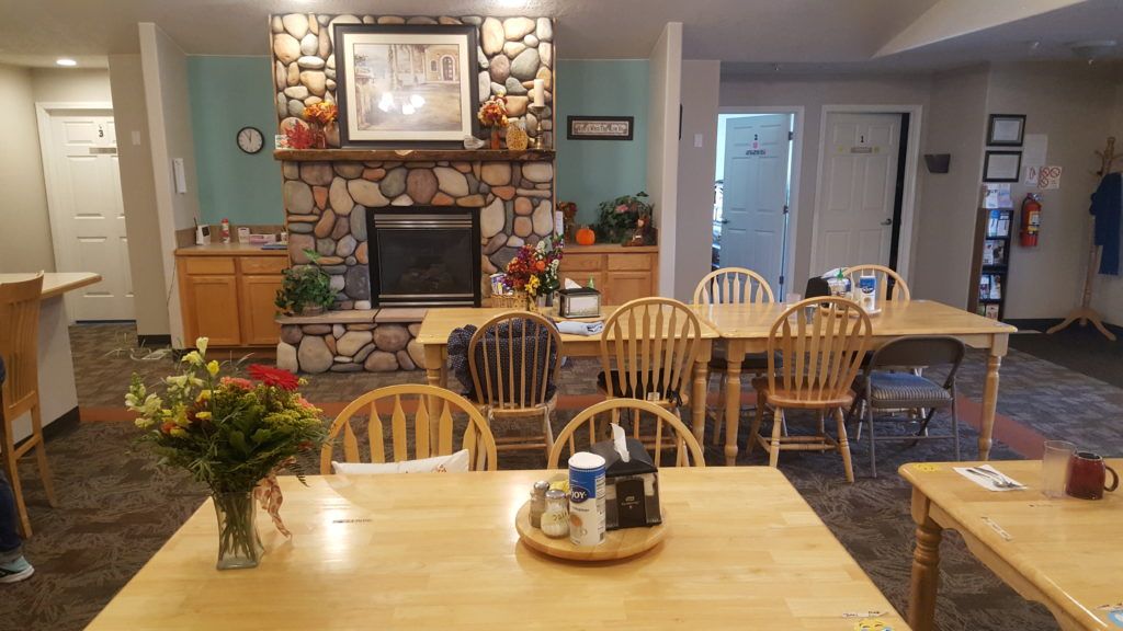 A cozy dining room with wooden furniture and a stone fireplace.