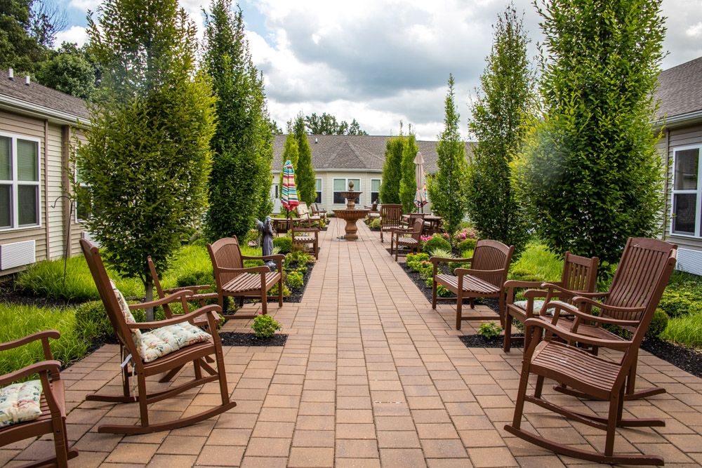 A beautifully landscaped garden path lined with chairs, leading to a quaint building.