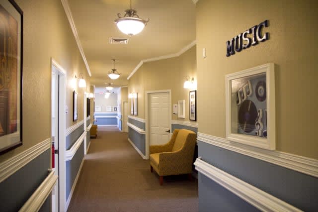A well-lit hallway with chairs and framed pictures on the walls.
