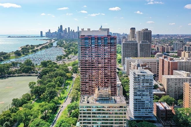 Aerial view of a cityscape featuring tall buildings and a nearby park with a distant skyline.