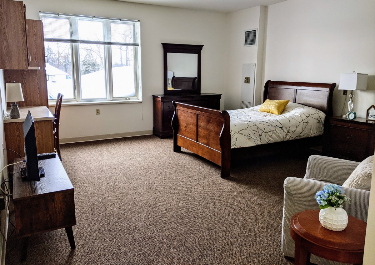 A cozy bedroom with a wooden single bed and matching furniture.