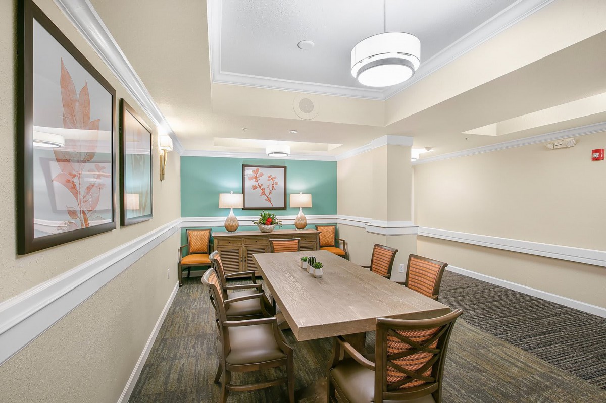 A well-lit dining or meeting room with a wooden table, chairs, and decorative artwork.
