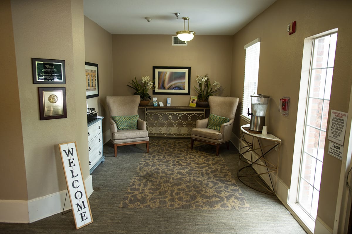 A cozy waiting area with two chairs, artwork, and decorative plants.