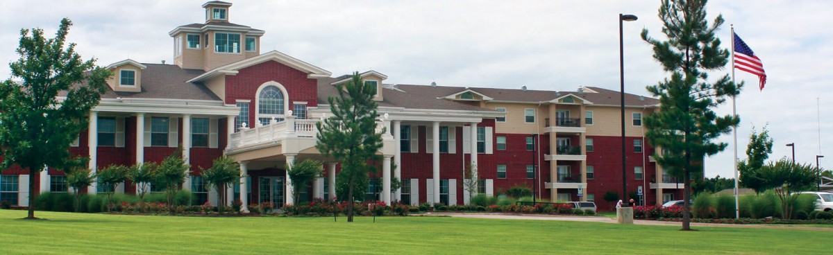 A red and white building with columns set amid a grassy landscape.