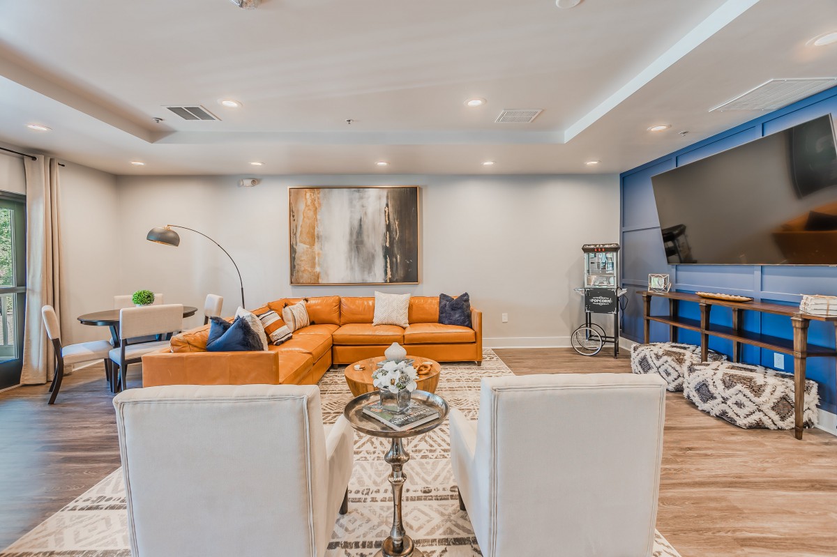 A modern living room with an orange sectional sofa, featuring stylish decor and contemporary artwork.