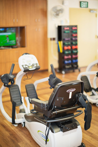 A well-equipped gym featuring a recumbent bike and a colorful storage area for fitness gear.