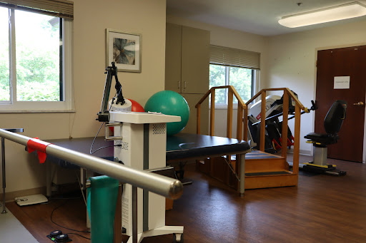 A well-equipped physical therapy room featuring exercise equipment, stairs for rehabilitation, and a green exercise ball.