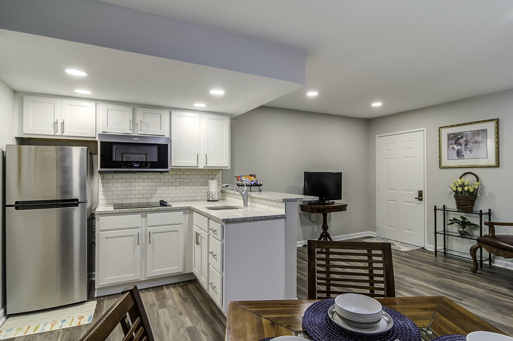 A modern open-concept kitchen with white cabinets and a small dining area.