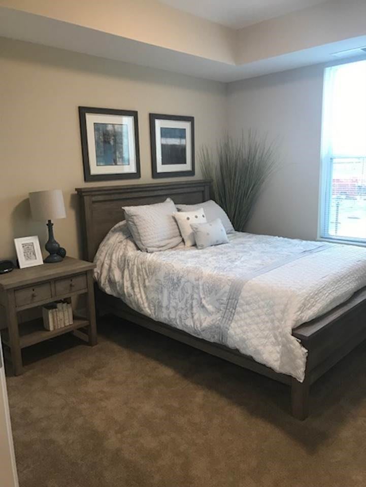 A cozy, well-decorated bedroom with a bed, nightstand, and framed pictures on the wall.