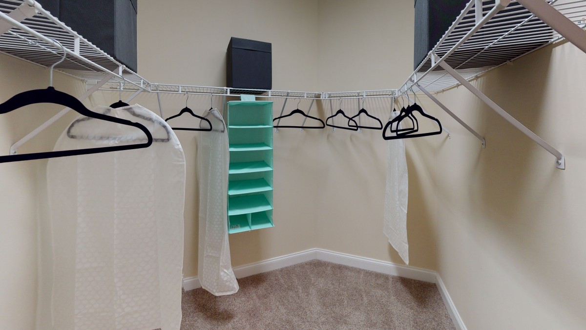 An empty walk-in closet with hangers and shelving for organizing clothes.