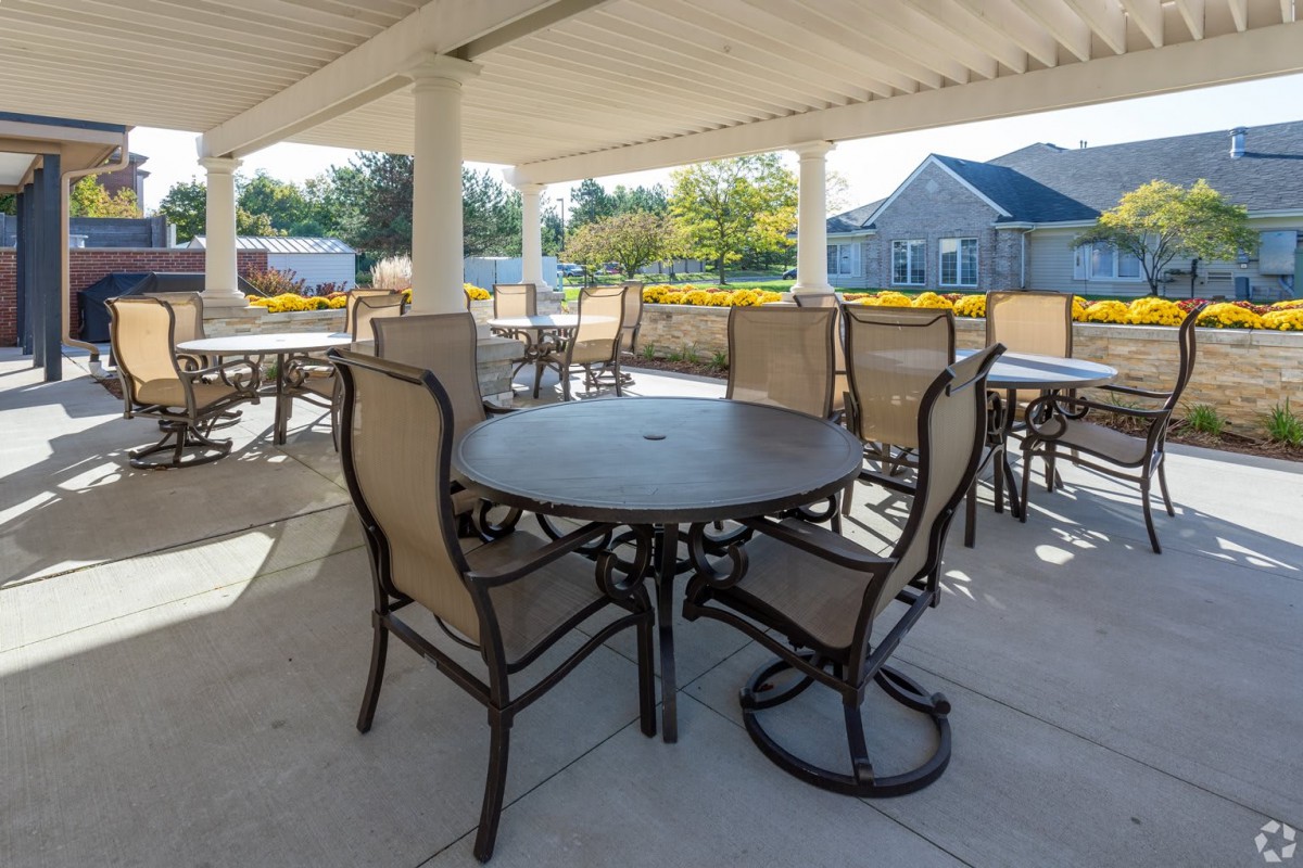 A covered outdoor seating area with tables and chairs on a sunny day.