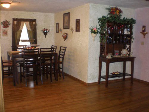 A dining room with a wooden table and chairs, decorated with wall art and greenery.