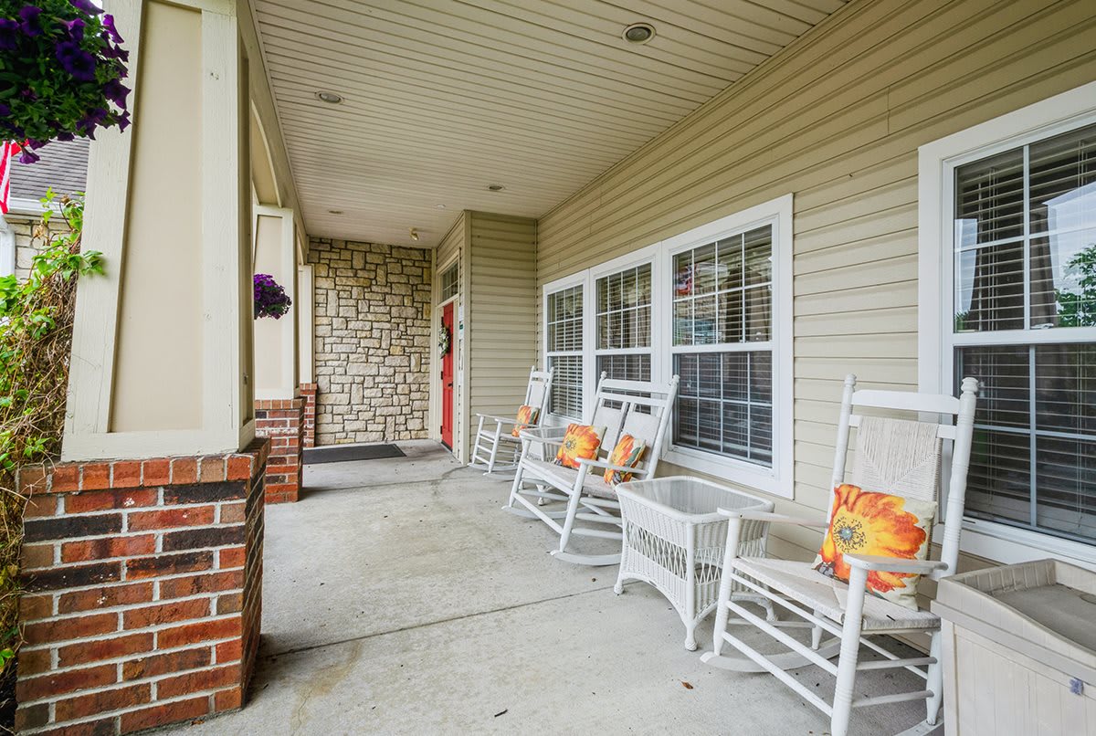 A cozy porch with white rocking chairs and decorative pillows.