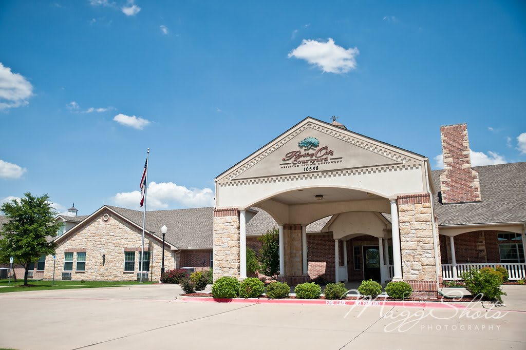 A large brick building with an arched entrance under a partly cloudy blue sky.