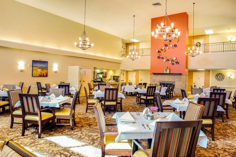 A spacious and elegantly designed dining room with chandeliers and neatly set tables.