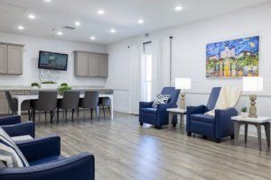 A modern living space featuring blue chairs and a dining area with hardwood flooring.