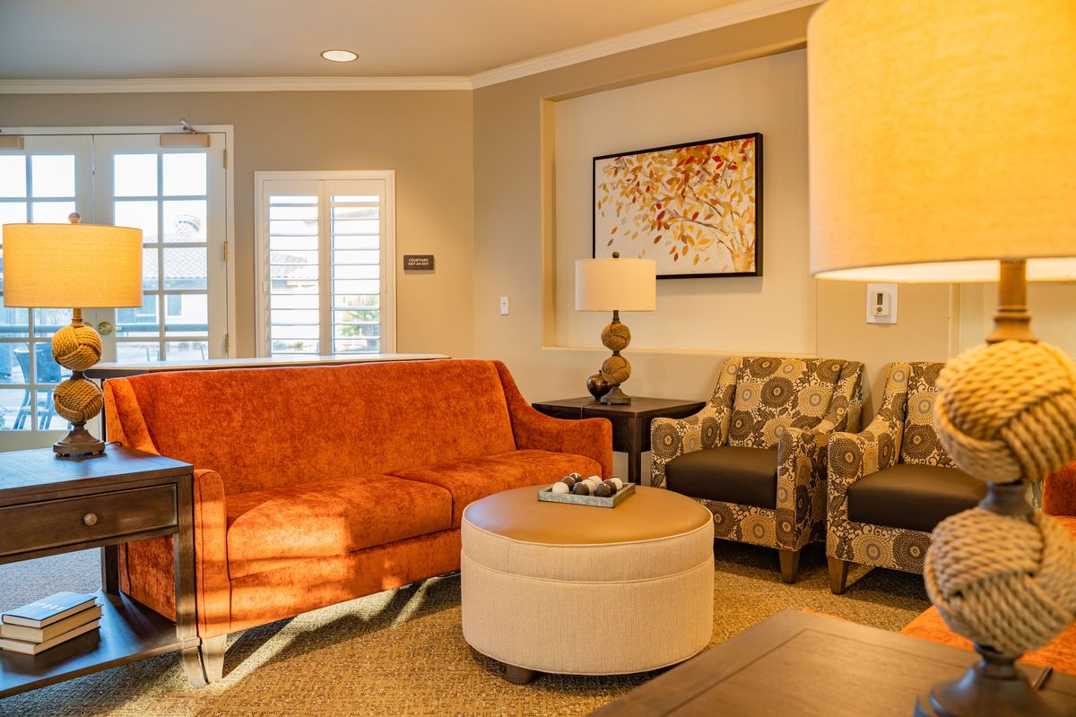 A cozy living room with an orange sofa, patterned armchairs, and a stylish coffee table.