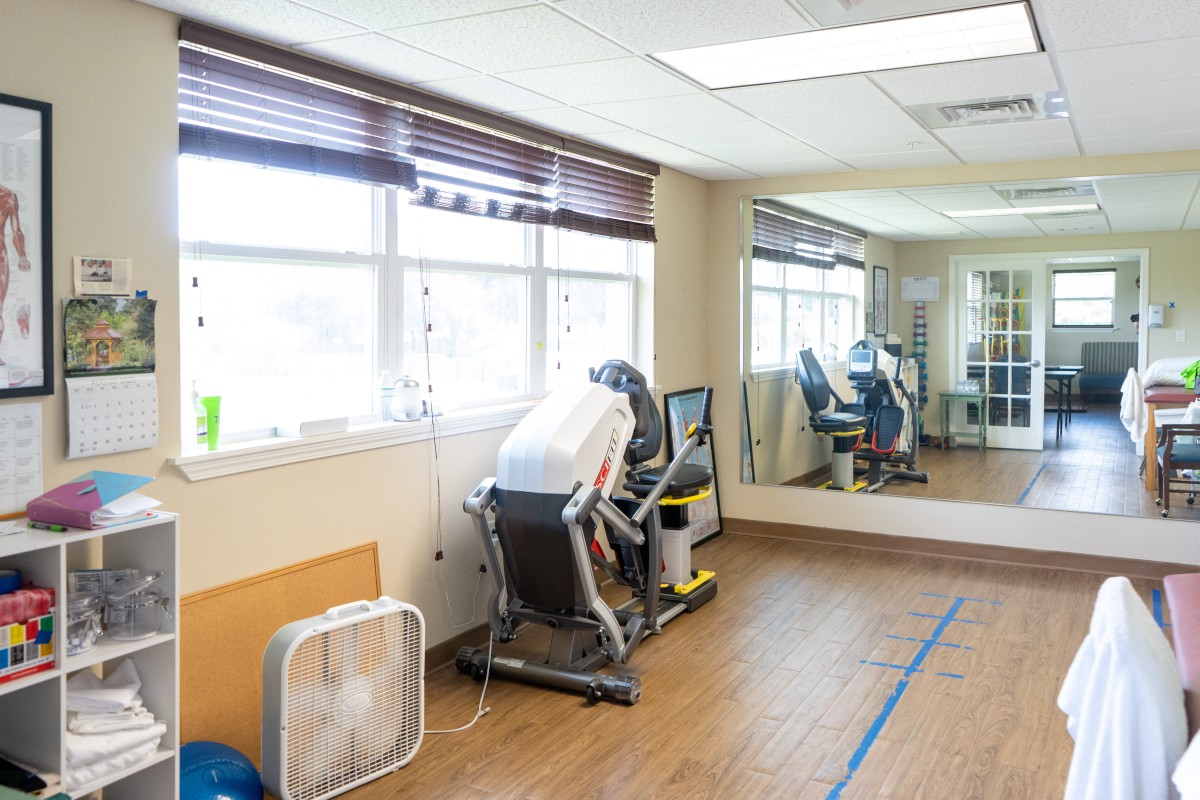 A therapy room with exercise equipment and large mirrors.