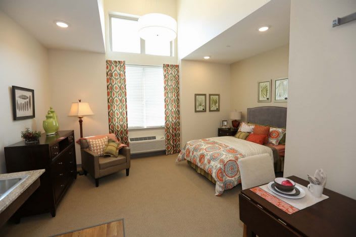 A cozy bedroom with a neatly made bed, armchair, and decorative elements.