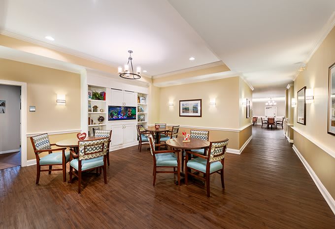 A cozy dining area with several tables and chairs, featuring elegant lighting and decor.