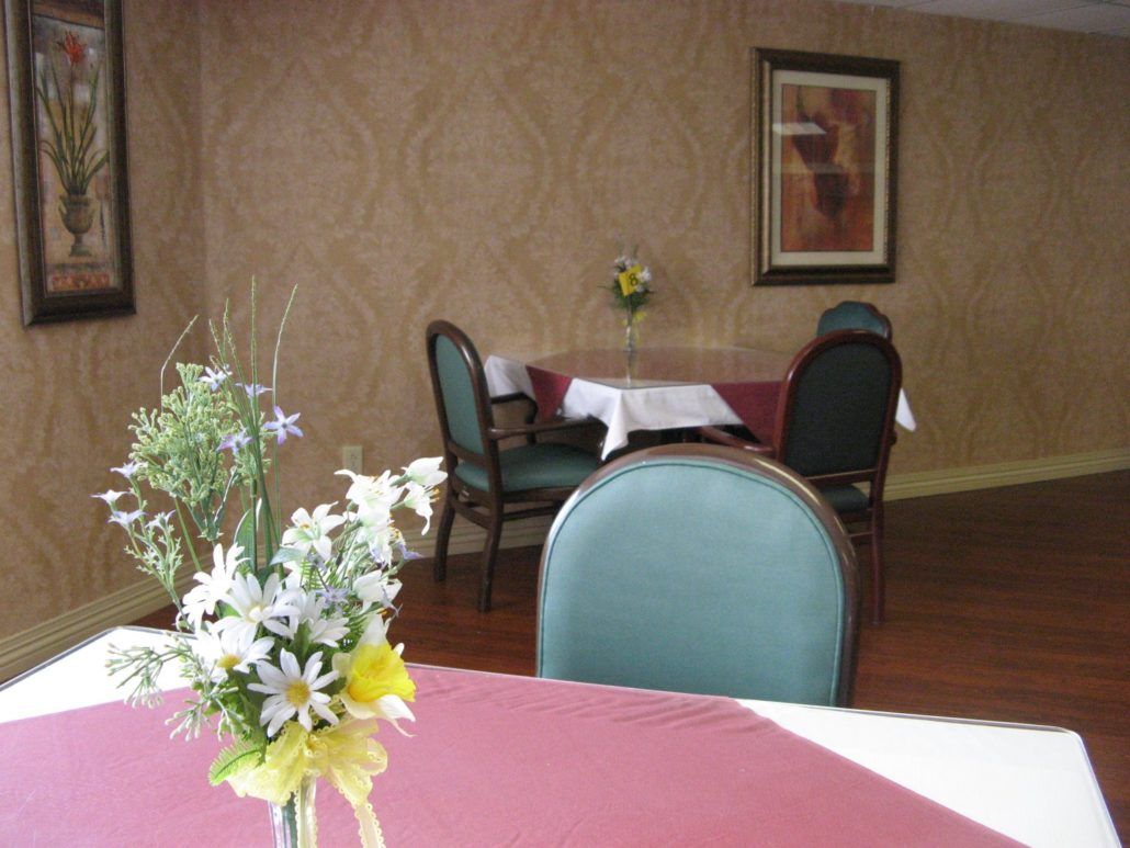 A small dining area with tables and chairs adorned with flowers.