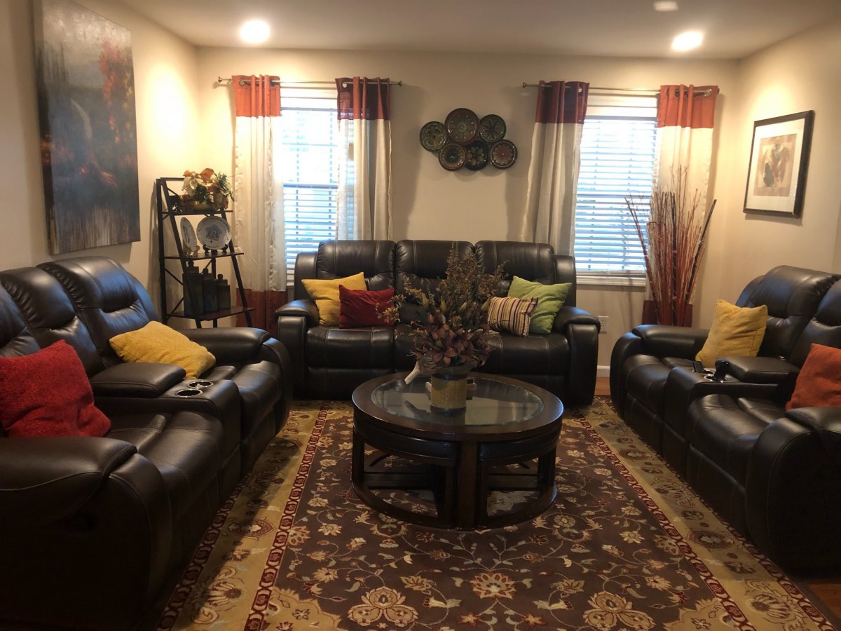 A cozy living room with leather sofas and colorful pillows, featuring a central coffee table and decorative elements.