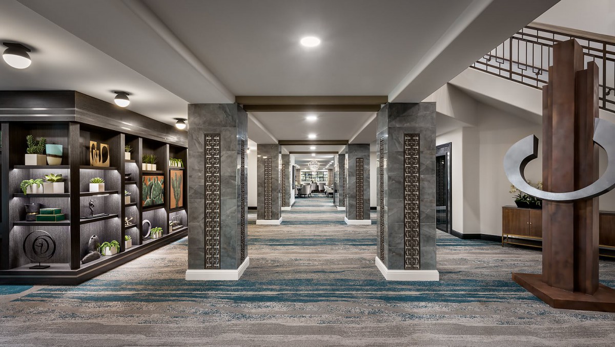 A modern, well-lit hallway with decorative pillars and textured flooring.